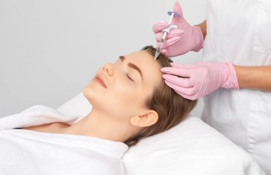 Kozmetik uzmanı güzel bir kadının yüzüne kırışıklık önleyici iğneler yapıyor. Güzellik salonunda kadın estetiği..