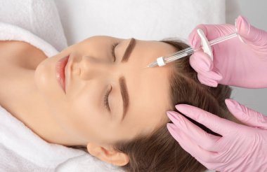 Kozmetik uzmanı güzel bir kadının yüzüne kırışıklık önleyici iğneler yapıyor. Güzellik salonunda kadın estetiği..