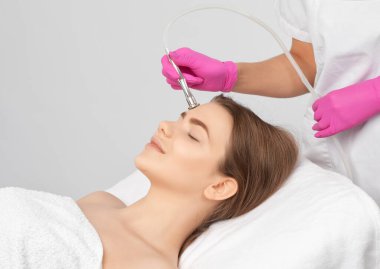 Kozmetik uzmanı, güzellik salonundaki güzel bir kızın yüzünün mikro cilt bakımını yapıyor. Kozmetoloji ve profesyonel cilt bakımı..