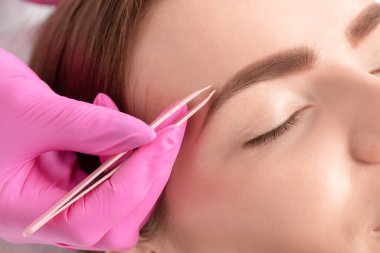 Makyöz güzellik salonunda kaş yoluyor. Profesyonel makyaj ve kozmetoloji cilt bakımı.