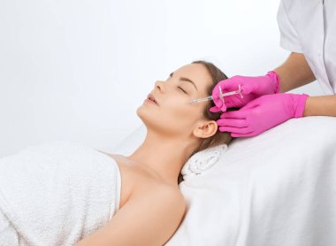 Kozmetik uzmanı güzel bir kadının yüzüne kırışıklık önleyici iğneler yapıyor. Güzellik salonunda kadın estetiği..