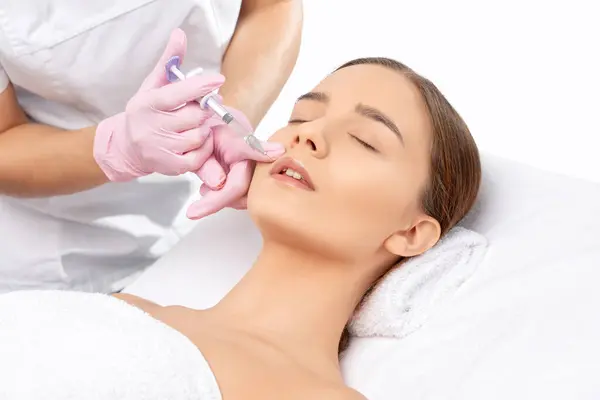 化粧品学者は 美しい女性の鼻腔壁の唇増強および反しわのための注射を行います 美容室における女性の化粧品 — ストック写真