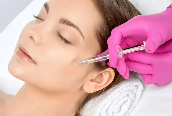 stock image Cosmetologist makes rejuvenating anti wrinkle injections on the face of a beautiful woman. Female aesthetic cosmetology in a beauty salon.