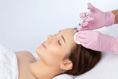 Kozmetik uzmanı güzellik salonunda güzel bir kadının yüzü üzerinde terapi uygular. Kozmetoloji kavramı.