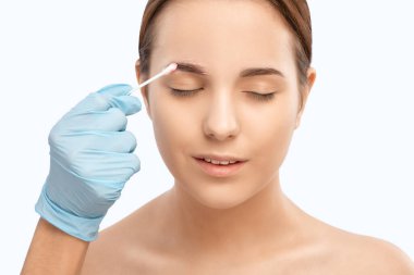 Makyaj sanatçısı kaşlar için beyaz kalemle işaretler yapar ve kaşları boyar. Profesyonel makyaj ve yüz bakımı.