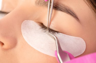 Güzellik salonunda uzun kirpikleri olan güzel bir kadın. Kirpik uzatma prosedürü. Kırbaçlar yakın.