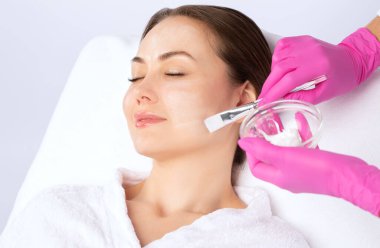 Güzellik uzmanı cildini tazelemek için kadın maskesi yapıyor. Yüz ve vücuttaki sorunlu cildin kozmetoloji tedavisi.