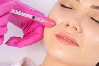 Kozmetik uzmanı güzel bir kadının yüzüne kırışıklık önleyici iğneler yapıyor. Güzellik salonunda kadın estetiği..