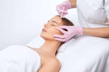 Kozmetik uzmanı güzel bir kadının yüzüne kırışıklık önleyici iğneler yapıyor. Güzellik salonunda kadın estetiği..