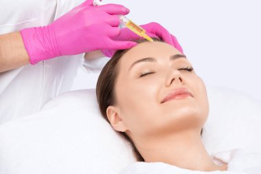 Kozmetik uzmanı güzel bir kadının yüzüne kırışıklık önleyici iğneler yapıyor. Güzellik salonunda kadın estetiği..