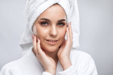 Beyaz önlüklü güzel esmer bir kızın portresi. Temiz ciltli ve makyajlı. Estetik kozmetoloji ve makyaj konsepti.