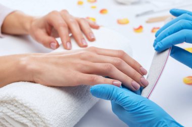 Manikür testeresinin ustası güzellik salonundaki tırnak uzatma işlemi sırasında tırnak şekli takıyor. Eller için profesyonel bakım.