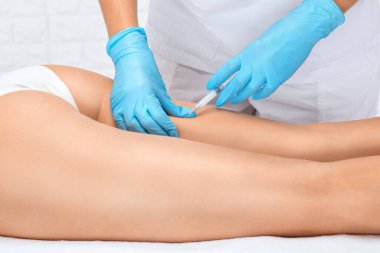 Estetik kozmetik uzmanı bir kadının kalçasında, kalçasında ve vücudunda yağ yakmak için lipolitik enjeksiyonlar yapar. Güzellik salonunda kadın estetiği. Kozmetoloji konsepti..