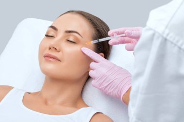 Kozmetik uzmanı güzel bir kadının yüzüne kırışıklık önleyici iğneler yapıyor. Güzellik salonunda kadın estetiği..