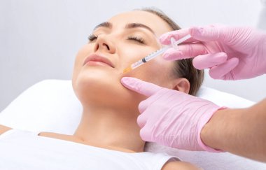 Kozmetik uzmanı güzel bir kadının yüzüne kırışıklık önleyici iğneler yapıyor. Güzellik salonunda kadın estetiği..