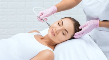 Kozmetik uzmanı yüzünde sivilce ve göz kenarındaki siyah noktalara karşı mikro dermabrüksiyon uygular. Güzellik salonunda kadın kozmetolojisi.