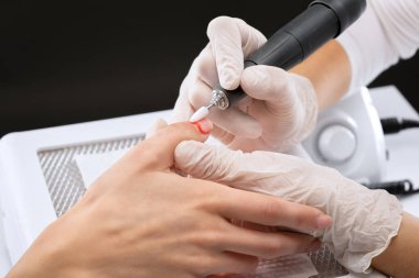 Manikür testeresinin ustası güzellik salonundaki tırnak uzatma işlemi sırasında tırnak şekli takıyor. Eller için profesyonel bakım.