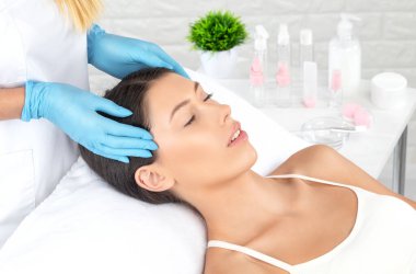 Masör, kaplıcadaki genç ve güzel bir kadının yüzüne, boynuna, omuzlarına ve köprücük kemiklerine rahatlatıcı bir masaj yapar. Kozmetoloji ve masaj konsepti.