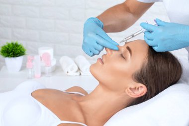 Kozmetik uzmanı güzel bir kadının yüzüne kırışıklık önleyici iğneler yapıyor. Güzellik salonunda kadın estetiği..