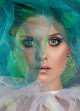 Güzel makyajlı çekici bir kızın portresi. Yüzünün yanında mavi-yeşil tül var..