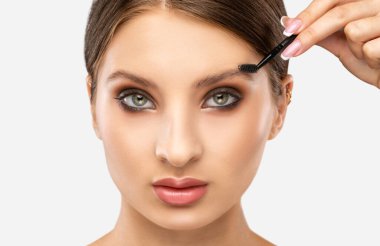 Makyöz güzellik salonunda kaşlarını tarar. Profesyonel makyaj ve estetik cilt bakımı.