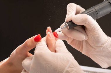Manikür testeresinin ustası güzellik salonundaki tırnak uzatma işlemi sırasında tırnak şekli takıyor. Eller için profesyonel bakım.