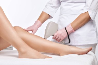Bir kadının vücudunda epilasyon tüy çıkarma prosedürü. Güzellik uzmanı bir güzellik salonunda bacağının alt kısmında lazer gençleştirme yapıyor. İstenmeyen vücut kılları alınıyor. Donanım ipl kozmetolojisi