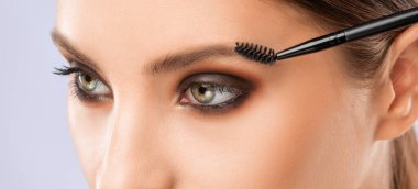 Makyöz güzellik salonunda kaşlarını tarar. Profesyonel makyaj ve estetik cilt bakımı.