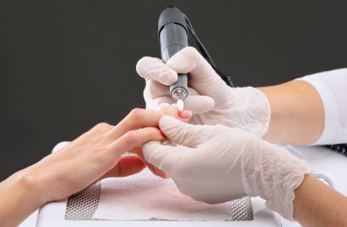 Manikür testeresinin ustası güzellik salonundaki tırnak uzatma işlemi sırasında tırnak şekli takıyor. Eller için profesyonel bakım.