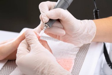 Manikür testeresinin ustası güzellik salonundaki tırnak uzatma işlemi sırasında tırnak şekli takıyor. Eller için profesyonel bakım.