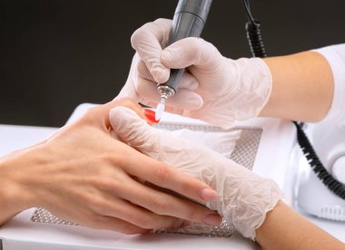 Manikür testeresinin ustası güzellik salonundaki tırnak uzatma işlemi sırasında tırnak şekli takıyor. Eller için profesyonel bakım.