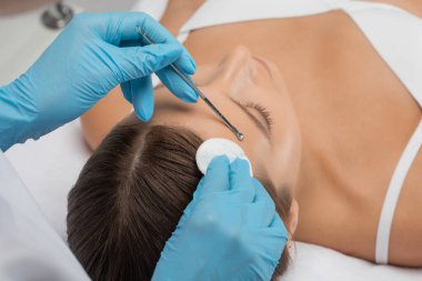 Yüzün siyah noktalarından ve sivilcelerden temizlenmesi için bir prosedür. Kozmetik uzmanı güzellik salonunda genç bir kadının sorunlu cildini tedavi ediyor. Estetik kozmetoloji ve makyaj konsepti.