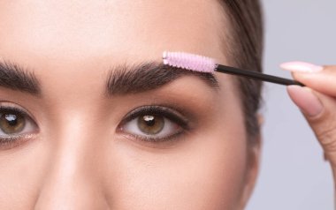 Makyöz bir güzellik salonunda kaşlarını tarar ve koparır. Profesyonel makyaj ve estetik cilt bakımı.