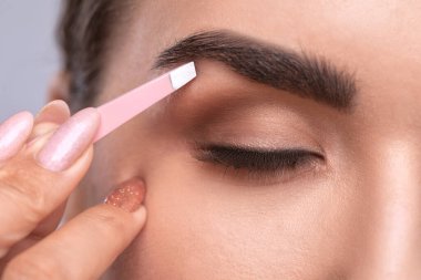 Makyöz bir güzellik salonunda kaşlarını tarar ve koparır. Profesyonel makyaj ve estetik cilt bakımı.