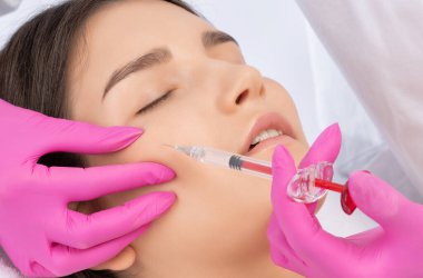 Kozmetik uzmanı güzel bir kadının yüzüne kırışıklık önleyici iğneler yapıyor. Güzellik salonunda kadın estetiği..