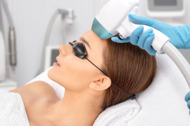 Elos epilasyon tüy çıkarma prosedürü bir kadının yüzünde. Güzellik uzmanı bir güzellik salonunda lazer gençleştirme yapıyor. Yüz bakımı. Donanım ipl kozmetolojisi