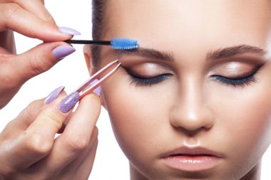 Makyöz bir güzellik salonunda kaşlarını tarar ve koparır. Profesyonel makyaj ve estetik cilt bakımı.