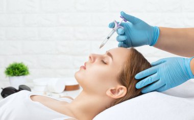 Doktor burundaki tümseği düzeltmek için iğne yapar. Güzellik uzmanı, yüzündeki kırışıklıklara karşı iğne yapar. Güzellik salonunda kadın kozmetolojisi.