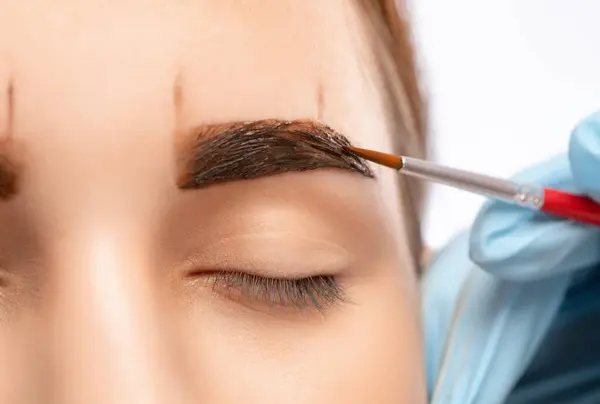Make-up artist makes markings for eyebrow and paints eyebrows. Professional makeup and facial care.