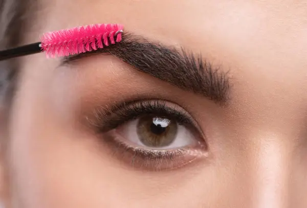 Makeup artist combs and plucks  eyebrows in a beauty salon. Professional make-up and cosmetic skin care.