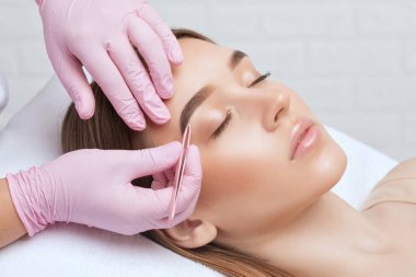 Makyaj sanatçısı boyama işleminden sonra kaşları yoluyor. Profesyonel makyaj ve yüz bakımı..