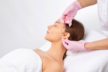 Kozmetik uzmanı güzel bir kadının yüzüne kırışıklık önleyici iğneler yapıyor. Güzellik salonunda kadın estetiği..