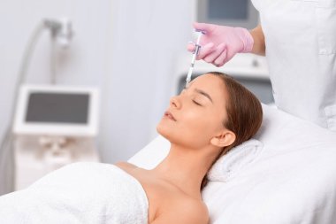 Kozmetik uzmanı güzel bir kadının yüzüne kırışıklık önleyici iğneler yapıyor. Güzellik salonunda kadın estetiği..