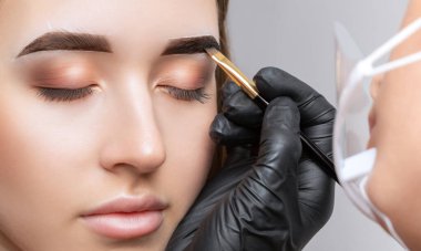 Makyaj sanatçısı kaşların uzun süreli stilini yapar ve kaşlarını boyar. Kaş kaplaması. Profesyonel makyaj ve yüz bakımı..