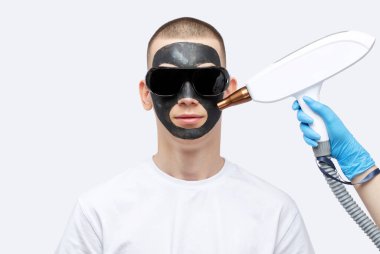 Güzellik uzmanı güzellik salonundaki yakışıklı adama karbon soyma işlemi yapıyor. Donanım erkek kozmetolojisi.