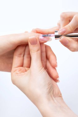 Manikür kürkünün ustası güzellik salonunda jöleyle oje sürüyor. Eller için profesyonel bakım.