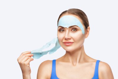 Bir güzellik uzmanı cildini tazelemek için bir kadının yüzü için aljinat mavi bir maske yapar. Yüzün ve vücudun sorunlu cildinin kozmetolojik tedavisi.