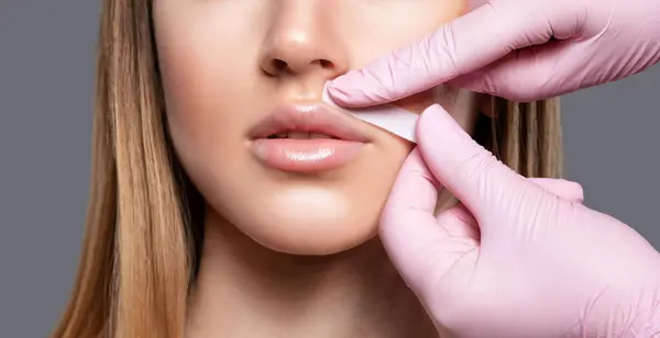 beautician makes a mustache removal with wax in a young woman. hair removal procedure on a womans body.