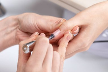 Manikür kürkünün ustası güzellik salonunda jöleyle oje sürüyor. Eller için profesyonel bakım.