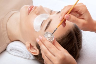 Makyöz, güzellik salonunda güzel bir kadına kirpik boyama ve kaplama prosedürünü uyguluyor. Kirpik uzantıları. Kirpik kaldırılıyor.